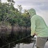 Angler using a fly rod on a river while wearing a Rep Your Water Flolite Sun Hoody in lichen