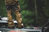 Angler fishing from a boat in rain while wearing Simms ProDry Fishing Bibs