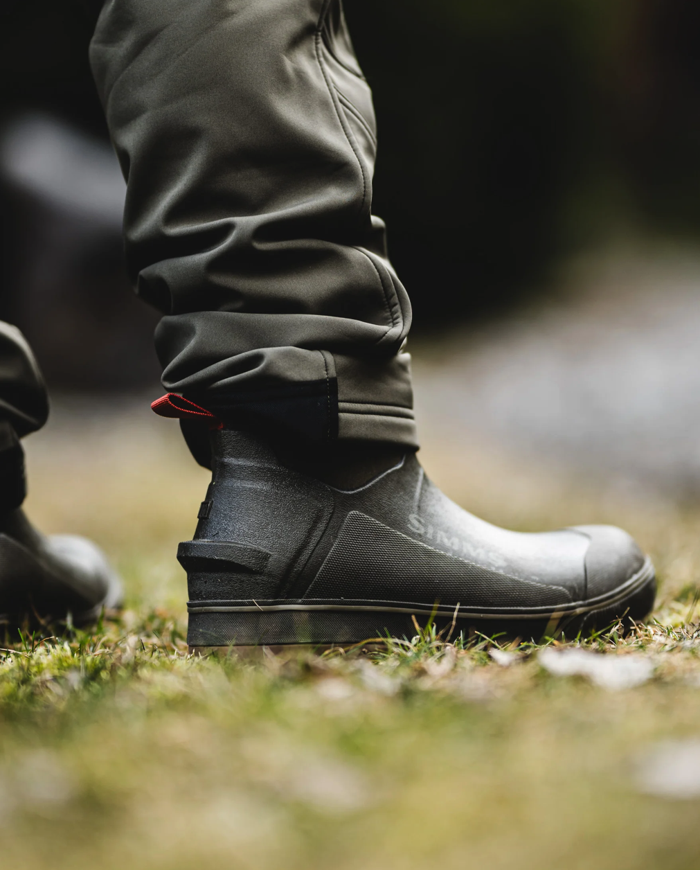 Lifestyle shot of Simms Challenger Slip-On fishing shoes worn by an angler, emphasizing their stylish and functional design.