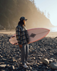 Person with surf board on beach wearing Simms Guide Fishing Pants.