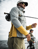 Fly angler with rod under arm and wearing Simms Latitude BiComp Shirt