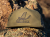 Yakoda Mayfly Hat in sage color on a rock ledge.